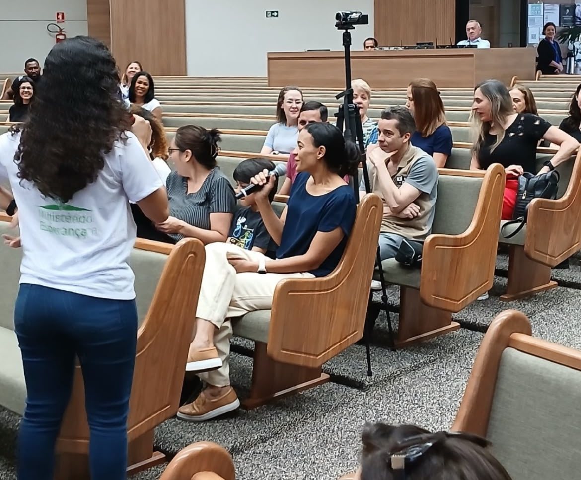 Voluntária do Ministério Esperança segurando o microfone para uma participante falar durante o encontro